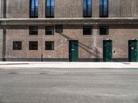 three doors sit outside of a brick building on the corner of a street and sidewalk