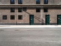 three doors sit outside of a brick building on the corner of a street and sidewalk