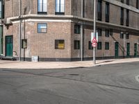 a red no left turn sign next to an empty street in a city environment of brick