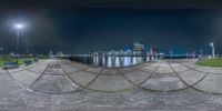 a wide angle view of a body of water at night with city lights in the distance