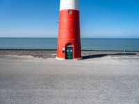 the lighthouse is sitting near the shore of the beach that stretches into the blue sea