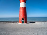 the lighthouse is sitting near the shore of the beach that stretches into the blue sea