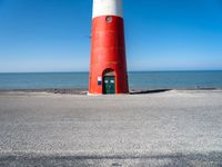 the lighthouse is sitting near the shore of the beach that stretches into the blue sea