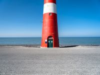 the lighthouse is sitting near the shore of the beach that stretches into the blue sea