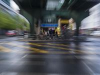 blurred photo of motorcycles and pedestrians on road under bridge in urban setting, high speed