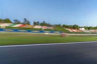 a person riding a motorcycle on a race track with trees in the background at sunset