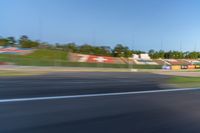 a person riding a motorcycle on a race track with trees in the background at sunset