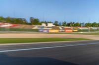 a person riding a motorcycle on a race track with trees in the background at sunset