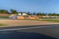 a person riding a motorcycle on a race track with trees in the background at sunset