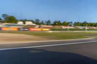 a person riding a motorcycle on a race track with trees in the background at sunset