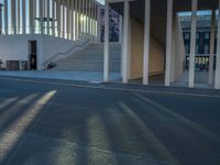 empty street lined with cement buildings next to a tall building with a staircase up to it