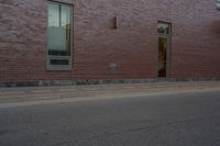 a skateboard on the street next to a brick building with windows and a yellow fire hydrant in front of it