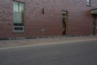 a skateboard on the street next to a brick building with windows and a yellow fire hydrant in front of it