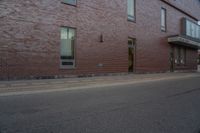 a skateboard on the street next to a brick building with windows and a yellow fire hydrant in front of it