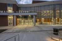 the glass entrance to martin center is illuminated by the evening sun, with some benches outside