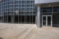 the entrance of an office building with large windows and some doors on either side of it