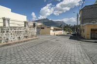 a view down the street in an area of stone and stucco, with the mountains in the distance