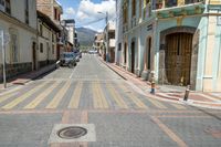 a small city street has parked cars on it, and no sidewalks are shown here