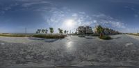 a fish eye picture of the sun setting on the beach and the road through the lens