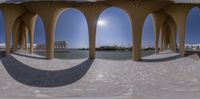 a circular shot with multiple circular arches at the bottom of them with buildings in the background