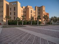 a small courtyard in front of an apartment building with palm trees in the middle of it