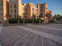 a small courtyard in front of an apartment building with palm trees in the middle of it