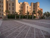 a small courtyard in front of an apartment building with palm trees in the middle of it