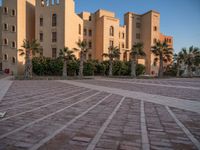 a small courtyard in front of an apartment building with palm trees in the middle of it