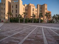 a small courtyard in front of an apartment building with palm trees in the middle of it