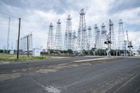 several electric towers that are in the middle of a street in front of a factory