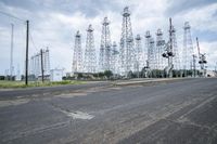 several electric towers that are in the middle of a street in front of a factory