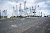 several electric towers that are in the middle of a street in front of a factory