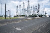 several electric towers that are in the middle of a street in front of a factory