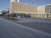 an electric tram that is going down the street on it's rails at a bus stop