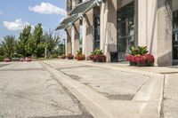 several flower pots sit in front of this very elegant building on the sidewalk outside the window