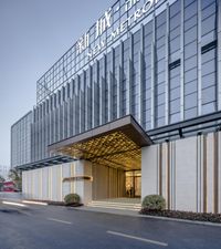 the entrance to the hotel has an elegant metal and glass facade with letters on it