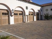 an elegant house with arched wooden garage doors outside, a driveway to the back of a home