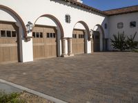 an elegant house with arched wooden garage doors outside, a driveway to the back of a home