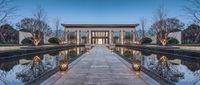 an elegant house with a modern architecture design in the evening time, as seen through the pond