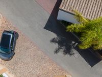 a view from above of a car driving down a sidewalk near a house with palm trees