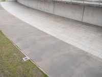 a skate boarder rides down an empty slope in a stadium ramp near the grass