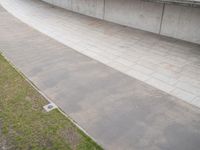 a skate boarder rides down an empty slope in a stadium ramp near the grass