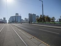 some people walking and riding a motorcycle over an elevated bridge between two sides of the city