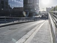 a walkway leads across an elevated bridge into a city street and there is a sun beam coming down