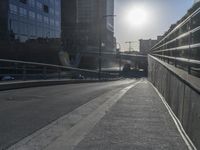a walkway leads across an elevated bridge into a city street and there is a sun beam coming down