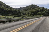 an empty road surrounded by some mountains in the wilds near a power pole that is over