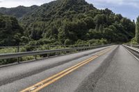 an empty road surrounded by some mountains in the wilds near a power pole that is over