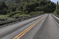 an empty road surrounded by some mountains in the wilds near a power pole that is over