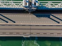 overhead shot of an elevated bridge in the ocean water, taken from above, which is visible to be a construction structure that supports a pedestrian - like a boat's