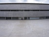 a building with cement roof near green grass and lawn in front of it, under a gray sky